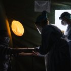 A nurse (R) and a doctor wearing personal protective equipment (PPE) in a tent on the grounds of the Sophiahemmet private hospital, perform tests on a patient to see if she has symptoms of COVID-19 on April 22, 2020 in Stockholm. - Those who are deemed not to be suffering from COVID-19 are allowed to go to a primary care centre for treatment for their condition while those who are presenting symptoms of the virus are told to return home to self-isolate or, in severe cases, sent to hospital for care (Photo by Jonathan NACKSTRAND / AFP)