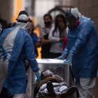 Un hombre de 20 años que se desmayó es conducido con todas las medidas de bioseguridad a una ambulancia este martes a las afueras de un centro comercial en Morelia, estado de Michoacán. EFE/ Iván Villanueva