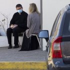 Catholic priest Jose, wearing a face mask, takes confession from a woman, as other faithful wait for their turn in their cars, outside the San Francisco de Asis church, in Santiago, on May 5, 2020. (Photo by CLAUDIO REYES / AFP)