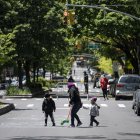 A woman plays with two children on a street, closed to vehicular traffic during a pilot program to provide more space for social distancing amid the novel coronavirus pandemic, on May 13, 2020 in Queens borough of New York City. (Photo by Johannes EISELE / AFP)