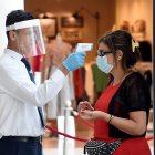 Un guardia de seguridad con mascarilla mientras controla la temperatura corporal de un cliente en un centro comercial de Beirut, Líbano.