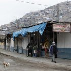 Un hombre con mascarilla camina frente a un puesto de venta de arreglos florales en las inmediaciones del Cementerio de Nueva Esperanza del distrito de Villa María del Triunfo, una de las zonas más populosas de Lima, capital de Perú.