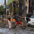 Una niña observa a su padre mientras recupera algunas de sus pertenencias tras las fuertes lluvias este miércoles en Kurume (Japón). Las precipitaciones torrenciales se extendieron hoy al centro de Japón, donde las autoridades han decretado la evacuación de más de 200.000 personas, después de dejar al menos 58 muertos en el sudoeste del país desde el fin de semana. EFE/ Kimimasa Mayama