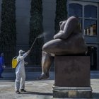 Un trabajador desinfecta una estatua de los artistas colombianos Fernando Botero, en Medellín, en medio de la pandemia de Covid-19