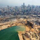 An aerial view taken on August 7, 2020, shows a partial view of the port of Beirut and the crater caused by the colossal explosion three days earlier of a huge pile of ammonium nitrate that had languished for years in a port warehouse, left scores of people dead or injured and caused devastation in the Lebanese capital. The city of Beirut can be seen in the background. (Photo by - / AFP)