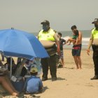 Dos agentes de policía desalojan a unos turistas que disfrutaban del balneario de Playas.