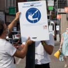 BRUSELAS. Un par de enfermeros colocan un anuncio promoviendo el uso de mascarillas en Woluwe-Saint-Lambert, aleñado a la capital de Bélgica.