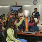 En una clase de Física, una alumna toca una esfera eléctrica. Los grupos de trabajo deben estimar el voltaje que recibió y explicarlo. Al fondo, el profesor Florencio Pinela.