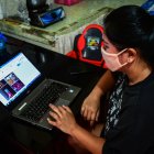 This photo taken on August 11, 2020 shows Lorraine Ann Imperio browsing her computer as she prepares to barter goods online in Las Pinas City, suburban Manila. - Struggling to make ends meet, Lorraine Imperio swapped a pair of Nike slip-ons for a whole dressed chicken on an online bartering site, one of dozens that have sprouted during the Philippines" virus lockdowns. (Photo by Maria TAN / AFP) / To go with AFP story Philippines-health-virus-lifestyle, FOCUS by Cecil Morella