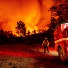 OROVILLE. Un bombero observa impasible cómo las llamas se elevan sobre su camión en el incendio en esta ciudad californiana la noche de este miércoles.