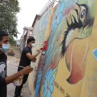 Los jóvenes vecinos pintan murales que bordean el Bosque Tropical.