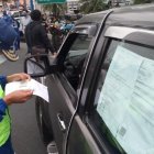 Un agente de la ATM lee un documento que le permite a un conductor circular.