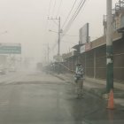 Ciudadanos en el cantón Jujan, del Guayas, esparcen agua en la calzada para evitar la dispersión de la ceniza.