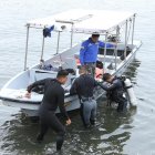 Buzos del Grupo de Intervención y Rescate (GIR), de la Policía Nacional, realizan la búsqueda del muchacho.