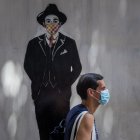 Una persona pasa frente a un mural de José Gregorio Hernández durante una ceremonia de exhumación de los restos del mismo hoy, en las inmediaciones de la iglesia de Nuestra Señora de La Candelaria, en Caracas