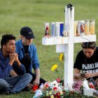 Mourners sit around one of 17 crosses at a memorial for the victims of the shooting at Marjory Stoneman Douglas High School in Parkland, Florida, U.S. February 16, 2018.  REUTERS/Jonathan Drake