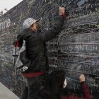 Una pareja escribe sus deseos post-pandemia en "El muro de la esperanza", en un parque del malecón de Lima.