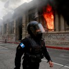 Un policía camina junto al fuego desatado, el 21 de noviembre de 2020, en el Congreso en Ciudad de Guatemala durante una jornada de protestas.