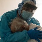 Médico abraza a paciente con covid, anciano, en cuidados intensivos.