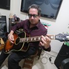 Abraham Cheing, juez y cantante en su despacho, tocando una de sus guitarras.