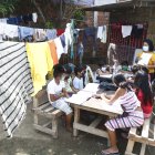 La ropa tendida en los cordeles, topa las cabezas de los niños que acuden al patio de una casa a realizar sus tareas escolares.