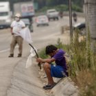 Un niño ondea una bandera blanca en la carretera pidiendo ayuda por hambre.
