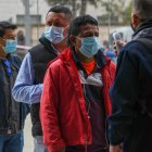 Un empleado le toma la temperatura a una ciudadana ecuatoriana residente en España vota en la segunda vuelta de las elecciones presidenciales de su país este domingo en el Palma Arena de Palma de Mallorca.