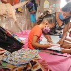 Una niña recibe clases en casa de la mano de su madre. Su hogar no cuenta con Internet.