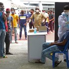 Un trabajador de salud toma una muestra nasal y un hisopo de un hombre para una prueba de COVID-19 en Bangalore, India.