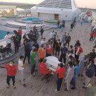 Los migrantes se reúnen en la proa del barco a escucharlo.