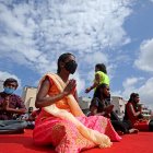 Niños con discapacidades visuales y entusiastas del yoga que usan mascarillas practican la meditación en el Día Internacional del Yoga en Bangalore, India.