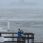 Dos hombres toman fotografías del comportamiento del mar frente a los fuertes vientos.