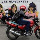 Dos motocicletas pasan frente a un mural que retrata a tres mujeres víctimas de violencia de género hoy, en Tegucigalpa (Honduras).