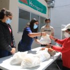 Intercambio. Alegría Parreño, Paula Herrera y Diego Yépez entregan una bolsa con alimentos a una beneficiaria de la fundación El Hormiguero.