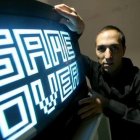 Fotografía cedida por el artista Yucef Merhi en la que aparece mientras posa junto a una de sus obras.