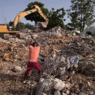 Un hombre recupera varillas de hierro para reutilizar en una área llena de escombros por la caída de un muro durante el terremoto . EFE/ Orlando Barría