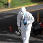 Un agente de la Dirección de Policía de Investigación inspecciona la escena donde un joven fue asesinado.