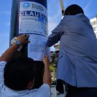 Momento en que el personal del Municipio de Guayaquil pega la sanción en el poste de una valla publicitaria.