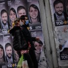 Una pareja camina frente a un cartel con la cara de Leandro Santoro, candidato a Diputado Nacional por el Frente de Todos, el 9 de septiembre de 2021, en la Ciudad de Buenos Aires (Argentina). Argentina volverá a las urnas este domingo para elegir en unas primarias abiertas a los candidatos que competirán en los comicios legislativos de noviembre próximo, un proceso electoral marcado por la pandemia de la covid-19. Unos 34,3 millones de argentinos están convocados para definir con su voto las listas de candidatos que quedarán habilitadas para competir en los comicios del 14 de noviembre, en los que se renovarán 127 de los 257 escaños de la Cámara de Diputados y 24 de las 72 bancas del Senado.
