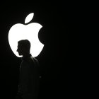 La silueta de un hombre se ve frente al logo de Apple, en una fotografía de archivo.