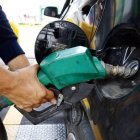 PISTOLA DE DISPENSADOR DE COMBUSTIBLE MIENTRAS LLENA EL TANQUE DE GASOLINA DE UN AUTO |