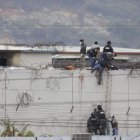 Sobre un muro del pabellón 2 se observa cómo se realizan pericias alrededor de un cadáver.