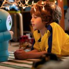 Un niño jugando con el robot Moxie en el suelo.