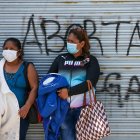 Dos mujeres permanecen frente a un rejado en el que se lee "Aborta", cerca de los exteriores de la Asamblea Nacional, el 1 de diciembre de 2021, en Quito (Ecuador).