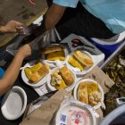 Voluntarios de la ONG "Regálame un Jajaja" reparten platos navideños durante una jornada de atención a personas en situación de calle, el 23 de diciembre de 2021 en Caracas (Venezuela).