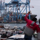 AME7422. VALPARAISO (CHILE), 12/11/2021.- Fotografía de archivo fechada el 15 de junio de 2020 que muestra a dos repartidores de domicilios mientras observan contenedores en el puerto de Valparaíso (Chile). Fertilizantes para la poderosa industria agropecuaria de Brasil, chips semiconductores para las automotrices mexicanas o falta de buques para exportar el café colombiano: Latinoamérica empieza también a sentir los efectos de la crisis global de suministros. Si bien la situación no es crítica, como en Estados Unidos, donde la campaña navideña está amenazada, la cadena de suministro en algunos países latinoamericanos comienza a estresarsel. EFE/ Alberto Valdés /ARCHIVO