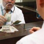 EMPLEADO O CAJERO DE BANCO CONTANDO DINERO EN LA VENTANILLA.