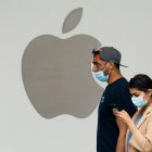 Una mujer usa un teléfono celular mientras camina frente a una tienda Apple, en una fotografía de archivo.