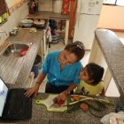 La profesora Carmita Agurto participa en una reunión de la escuela mientras atiende a una de sus hijas.