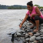 Una madre de familia mueve las machas de crudo que hay en las orillas del río Napo.